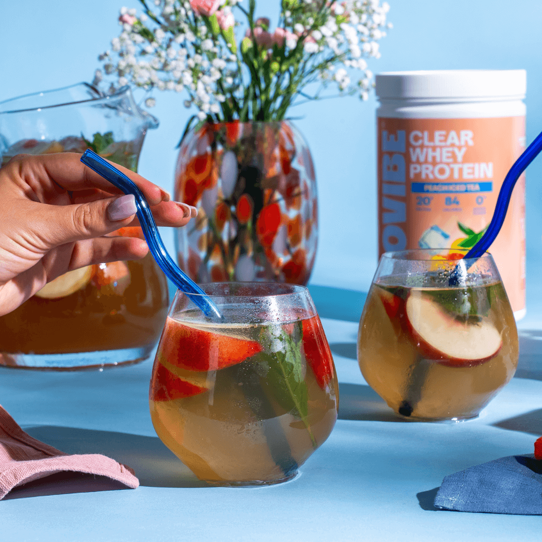 Peach Iced Tea on blue backdrop with jug of ISOVIBE, the tub and two glasses