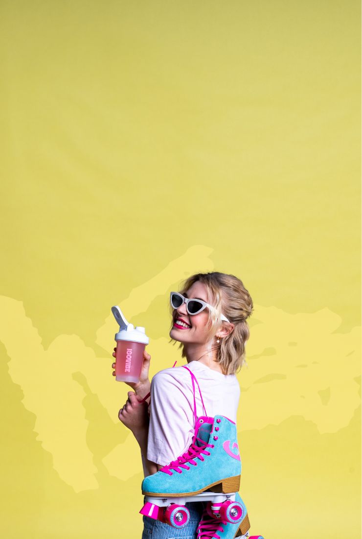 Girl with blue and pink roller skates over her shoulder, holding an ISOVIBE shaker on a bright yellow background