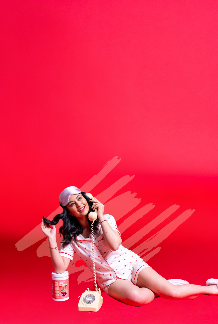 Girl in pyjamas holding a retro telephone leaning on a tub of Sour Cherry ISOVIBE  on a bright red background