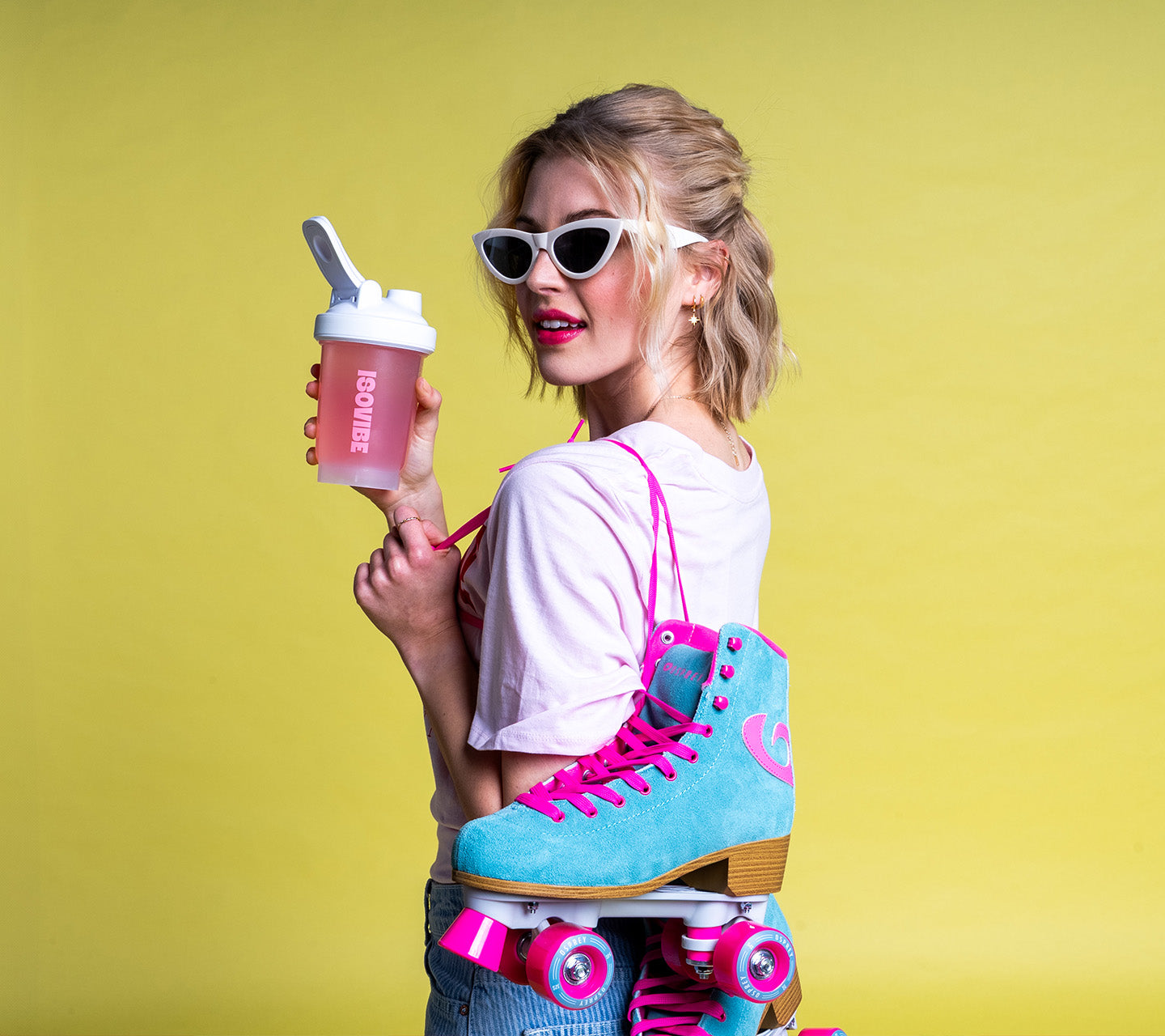 pink lemonade isovibe drink being drunk by young female holding isovibe shaker, with roller skates in another hand
